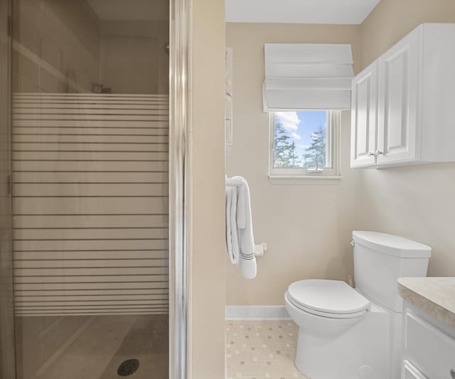 full bathroom featuring vanity, baseboards, toilet, and a shower stall
