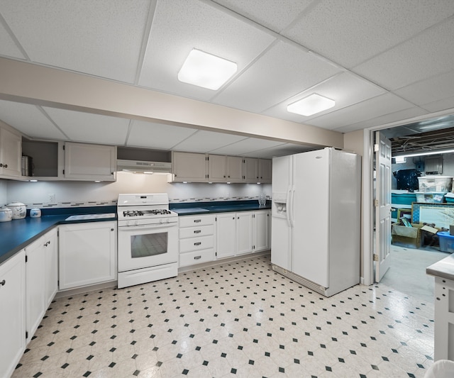 kitchen featuring dark countertops, under cabinet range hood, white appliances, and light floors