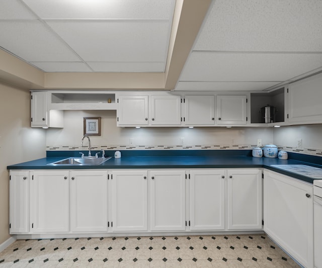 kitchen with a paneled ceiling, dark countertops, open shelves, a sink, and white cabinets