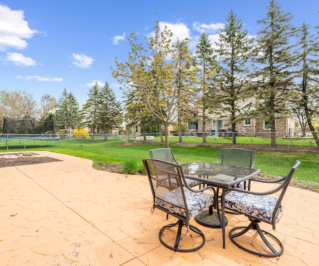 view of patio with a fenced backyard, a trampoline, and outdoor dining area