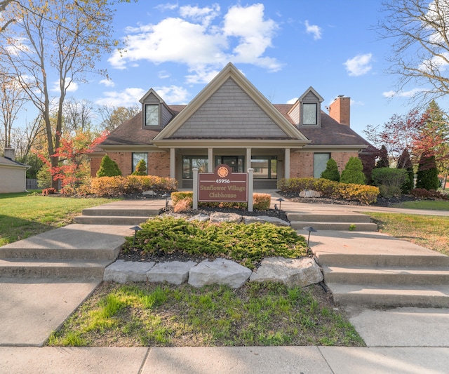 view of front facade with brick siding and a chimney