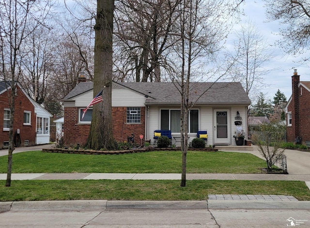 ranch-style house with roof with shingles, a front yard, and brick siding