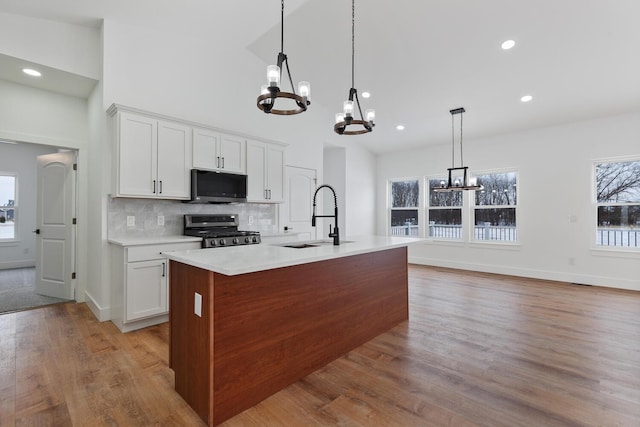 kitchen with light countertops, gas range oven, a sink, and a notable chandelier