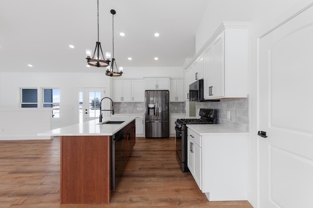 kitchen featuring an inviting chandelier, black microwave, refrigerator with ice dispenser, a sink, and range with gas cooktop