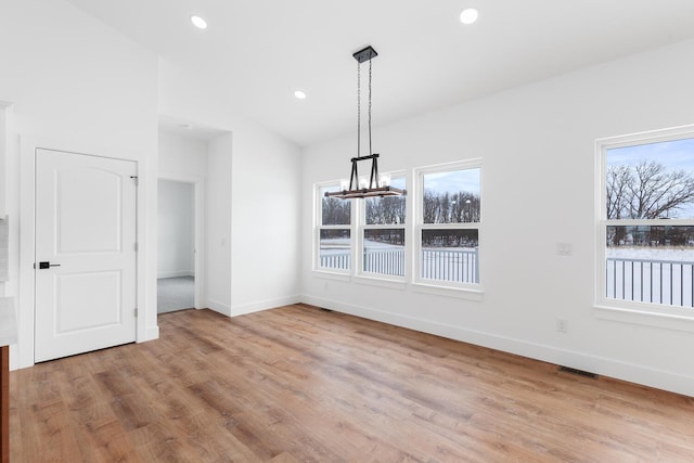 unfurnished dining area with a wealth of natural light, visible vents, an inviting chandelier, and wood finished floors