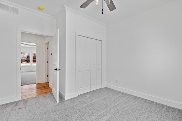 unfurnished bedroom with carpet, a closet, ornamental molding, visible vents, and baseboards