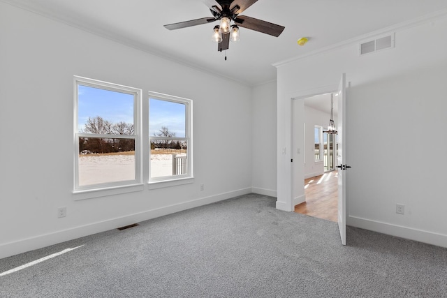 spare room with visible vents, baseboards, ornamental molding, a ceiling fan, and light carpet
