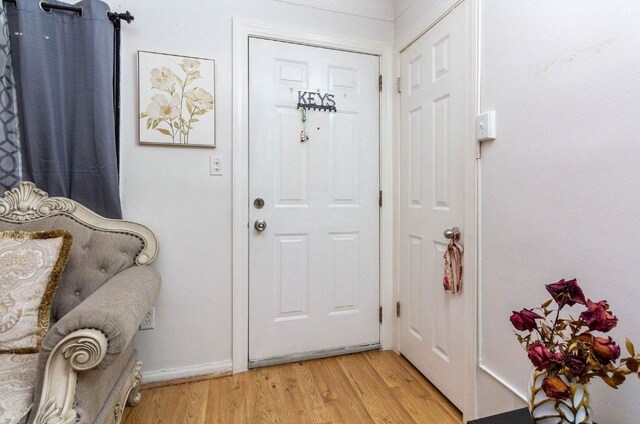 doorway featuring light wood finished floors and baseboards