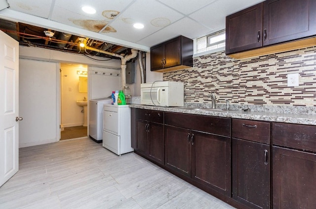 laundry room with electric panel, cabinet space, washer and dryer, light wood finished floors, and a sink