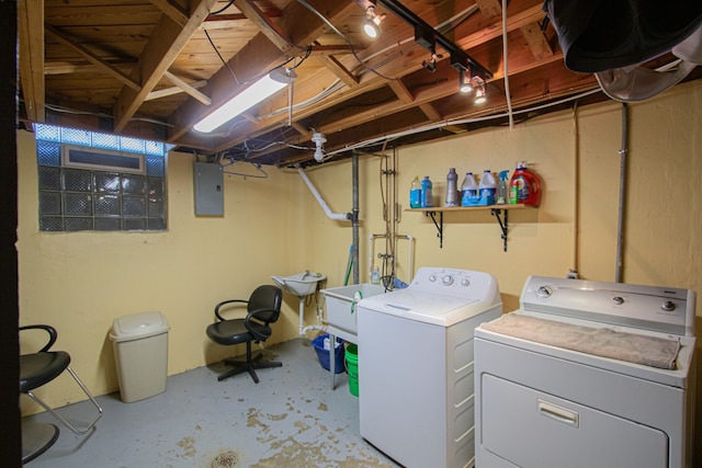 washroom featuring electric panel, a sink, washer and clothes dryer, and laundry area