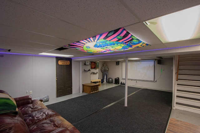 finished below grade area with a paneled ceiling and stairway