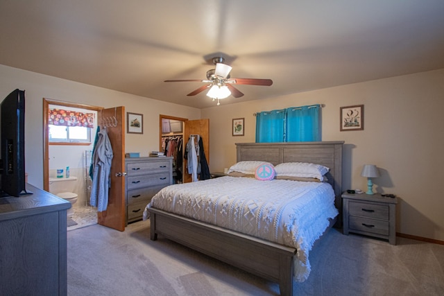 bedroom with a spacious closet, a ceiling fan, light carpet, a closet, and ensuite bathroom