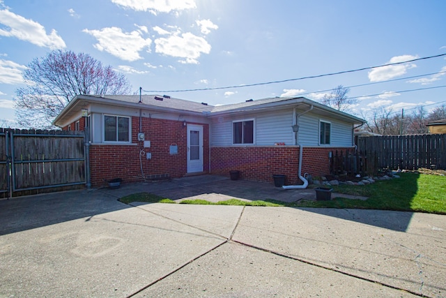 view of front facade featuring fence, a patio area, and brick siding