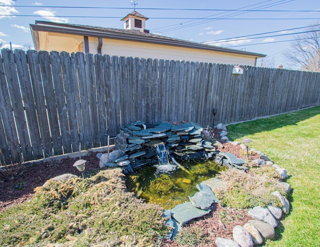 view of yard featuring fence and a small pond