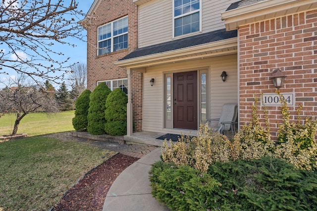 property entrance featuring brick siding and a yard