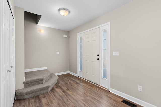 foyer with baseboards, visible vents, wood finished floors, and stairway