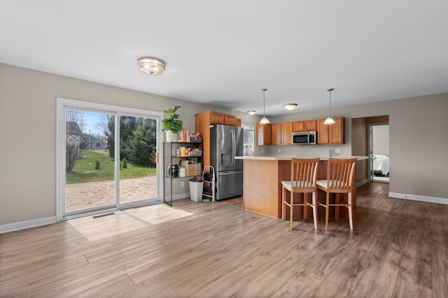 kitchen with light countertops, stainless steel appliances, visible vents, and light wood-style floors