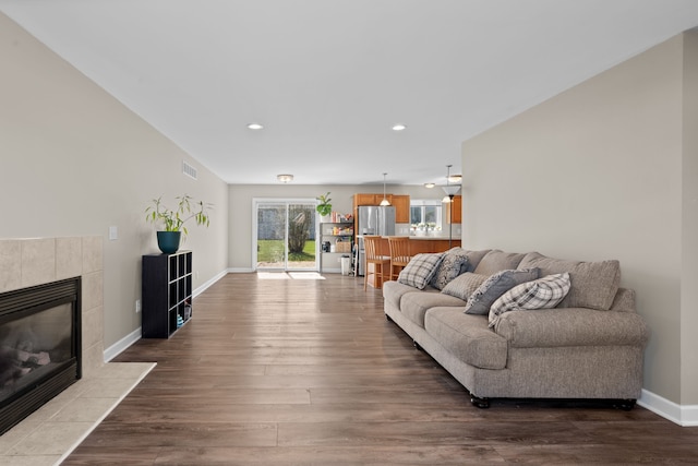 living area featuring visible vents, wood finished floors, a fireplace, baseboards, and recessed lighting