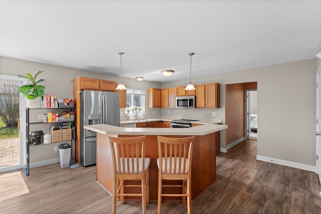 kitchen featuring light countertops, appliances with stainless steel finishes, a center island, and wood finished floors
