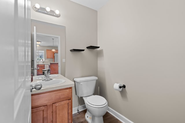 bathroom with vanity, baseboards, wood finished floors, and toilet