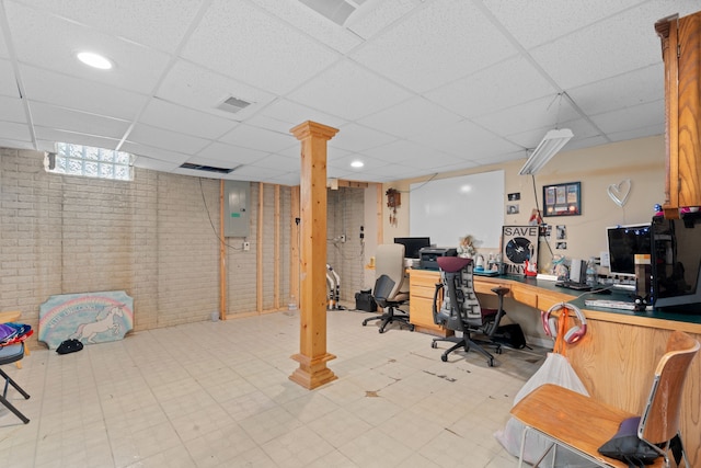 office space with tile patterned floors, a drop ceiling, brick wall, and visible vents