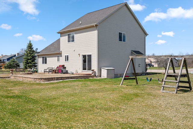 back of house with a playground, a yard, a patio area, and roof with shingles