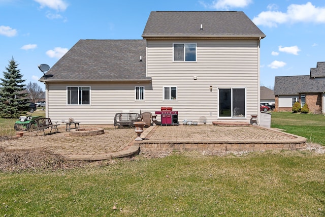 back of property featuring a lawn, a shingled roof, a patio area, and a fire pit