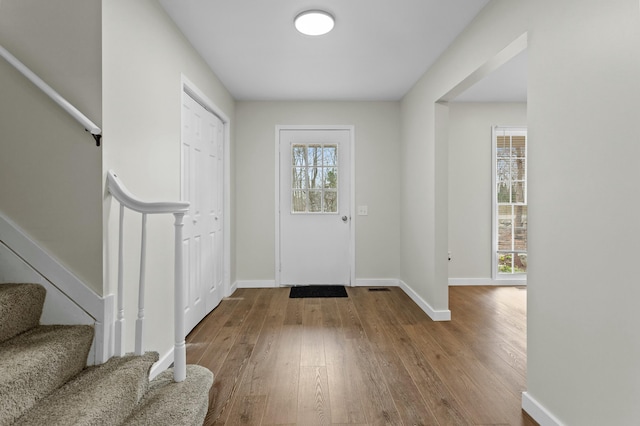 foyer entrance with wood-type flooring, baseboards, and stairway