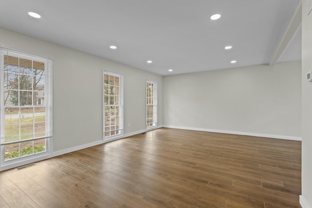 spare room with a wealth of natural light, visible vents, and wood finished floors