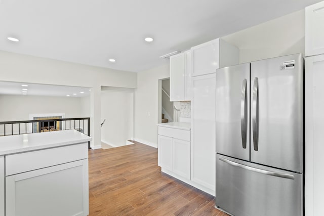 kitchen with light countertops, light wood-type flooring, white cabinetry, and freestanding refrigerator
