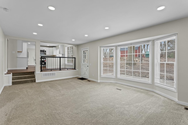 unfurnished living room with recessed lighting, carpet, baseboards, and a healthy amount of sunlight