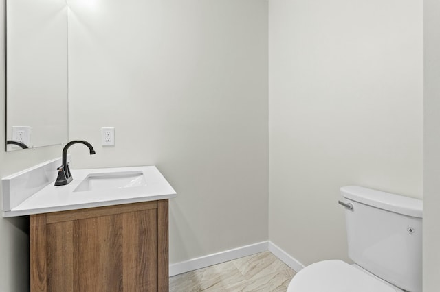 half bath with vanity, baseboards, and toilet