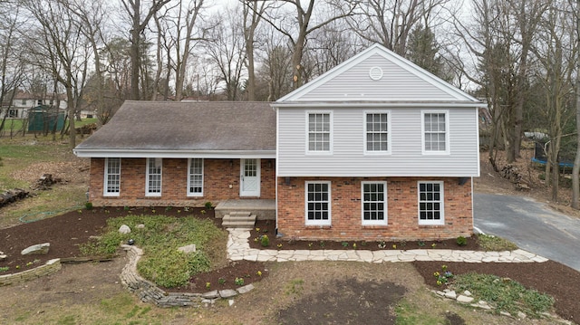 tri-level home featuring brick siding and a shingled roof