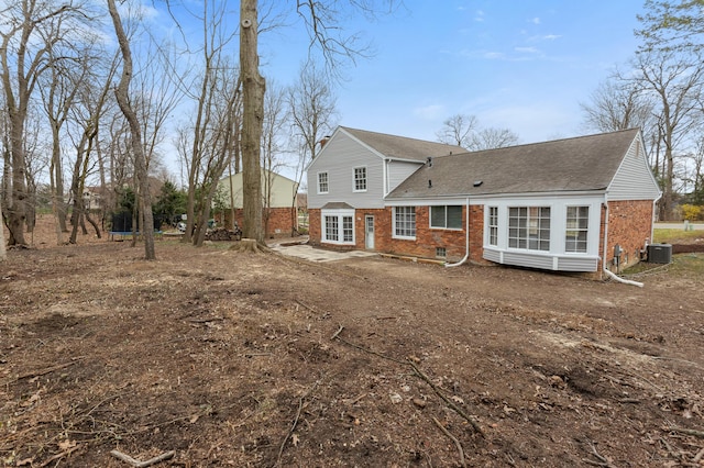 back of property with central AC unit and brick siding