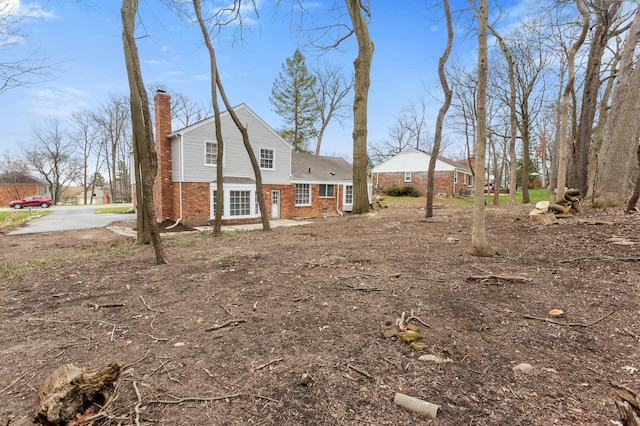 exterior space featuring brick siding and a chimney
