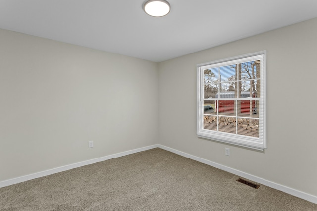 carpeted spare room featuring visible vents and baseboards