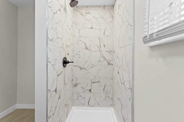 bathroom featuring baseboards, tiled shower, and wood finished floors