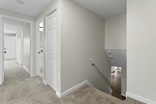 hallway with baseboards, an upstairs landing, and carpet