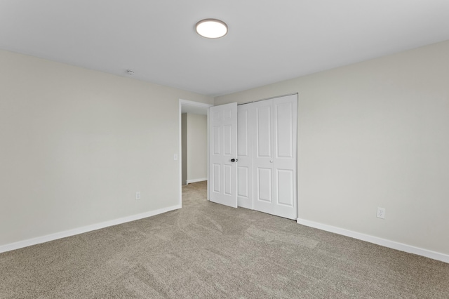 unfurnished bedroom with a closet, baseboards, and carpet