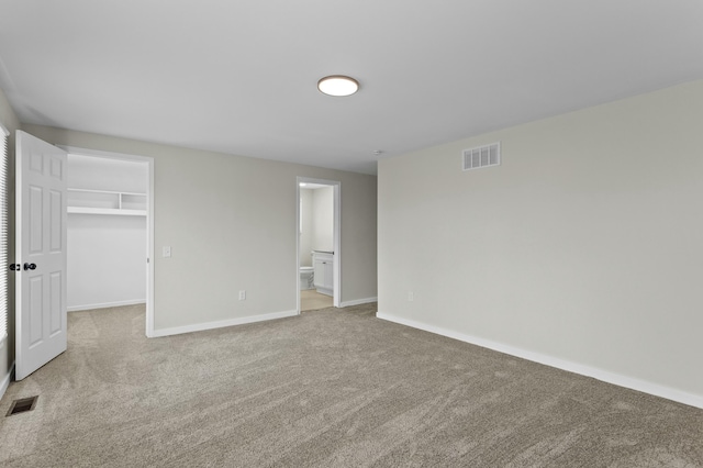 unfurnished bedroom featuring visible vents, a spacious closet, carpet floors, and baseboards