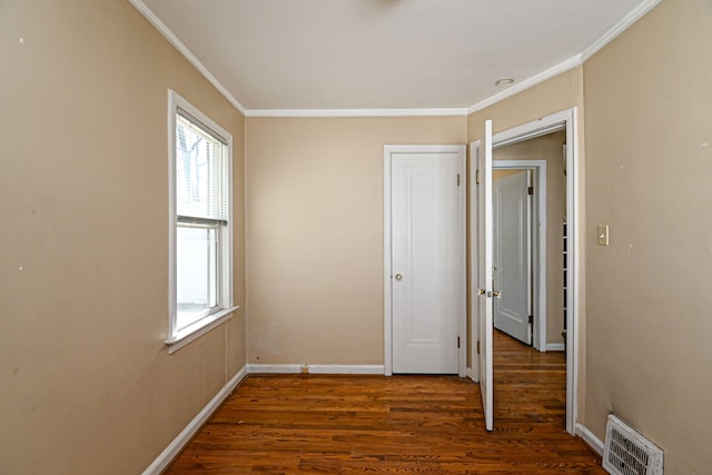 unfurnished bedroom featuring multiple windows, crown molding, wood finished floors, and baseboards