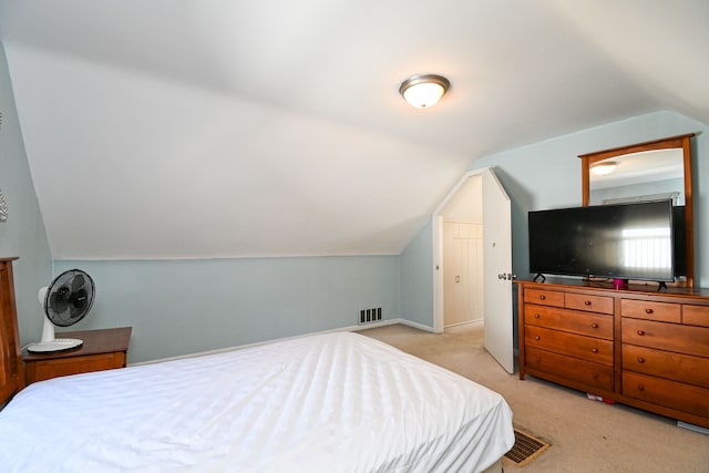 bedroom with vaulted ceiling, light colored carpet, and baseboards