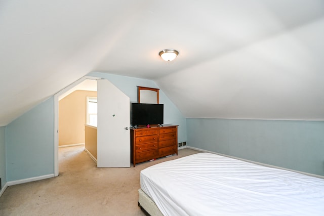 bedroom featuring lofted ceiling, light carpet, and baseboards