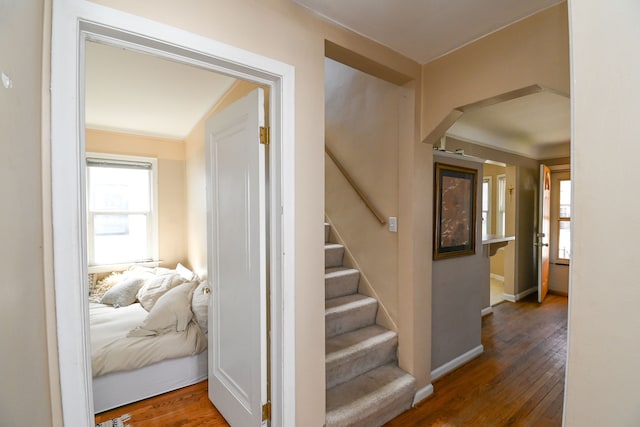 stairs with arched walkways, hardwood / wood-style flooring, and baseboards
