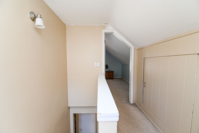 corridor with vaulted ceiling and light colored carpet