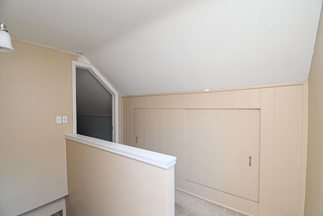 hall with lofted ceiling, carpet flooring, and an upstairs landing