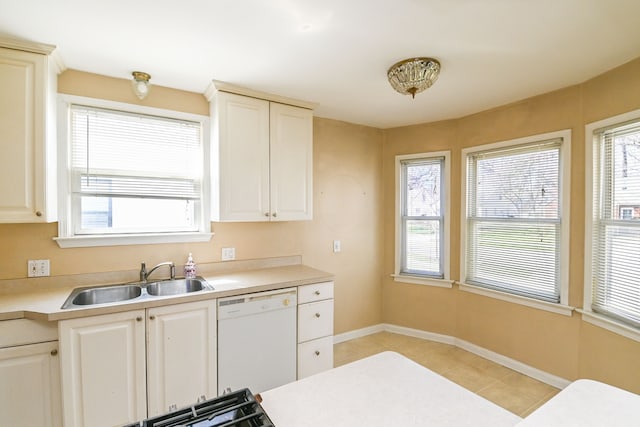 kitchen with white dishwasher, a sink, light countertops, and healthy amount of natural light