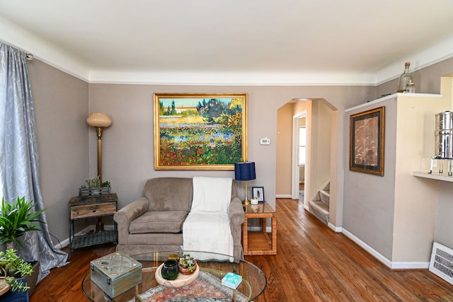 living area featuring arched walkways, stairs, wood finished floors, and baseboards