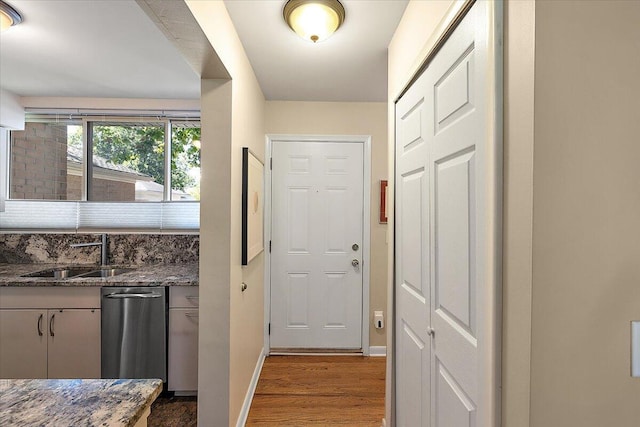 doorway with wood finished floors, a sink, and baseboards