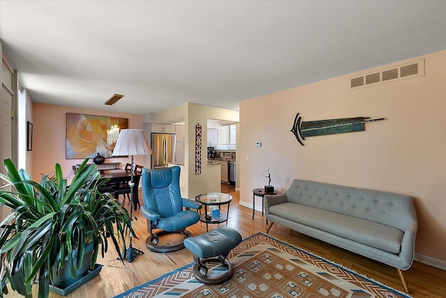 living area with wood finished floors, baseboards, and visible vents